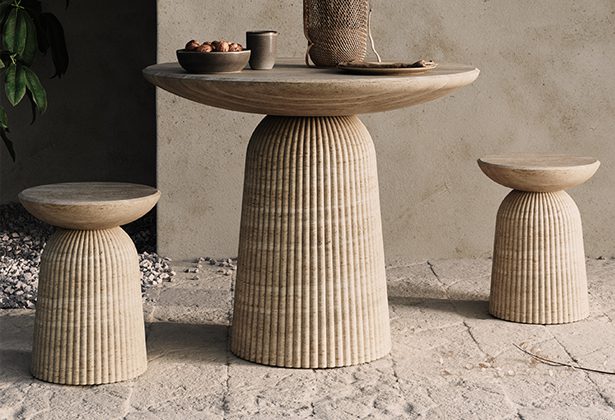 A table and two stools are sitting on the ground.